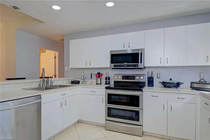 Kitchen with appliances with stainless steel finishes, light countertops, white cabinetry, recessed lighting, and light tile patterned floors