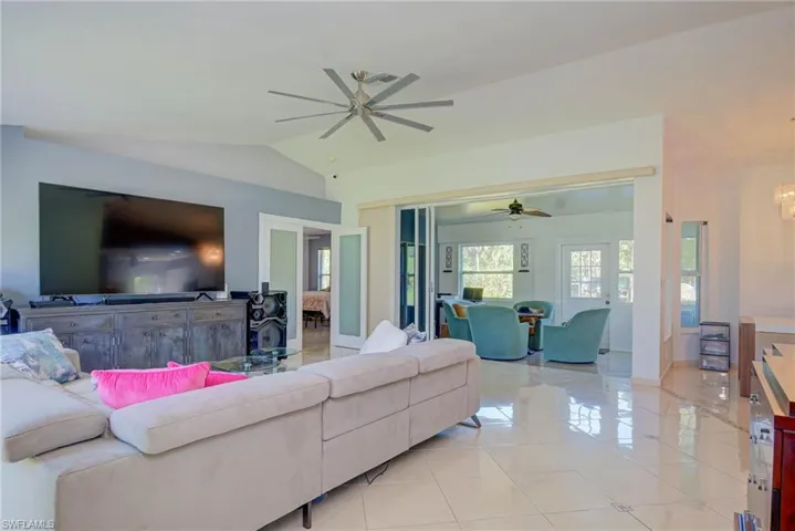 Living area featuring a ceiling fan, lofted ceiling, and light tile patterned floors
