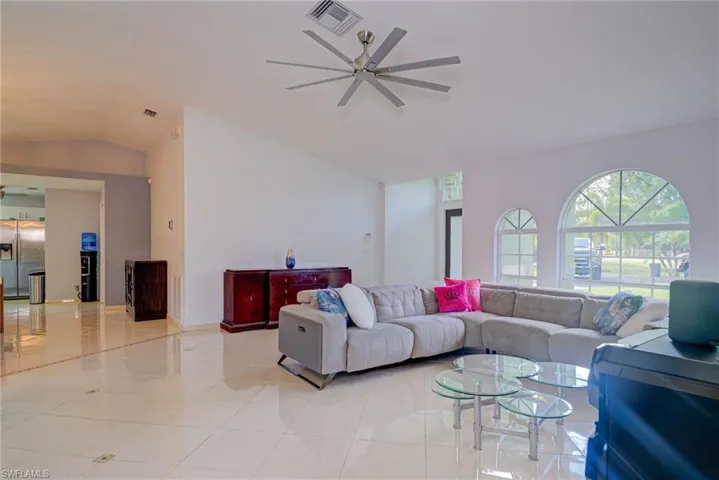 Living room with vaulted ceiling, ceiling fan, and light tile patterned floors