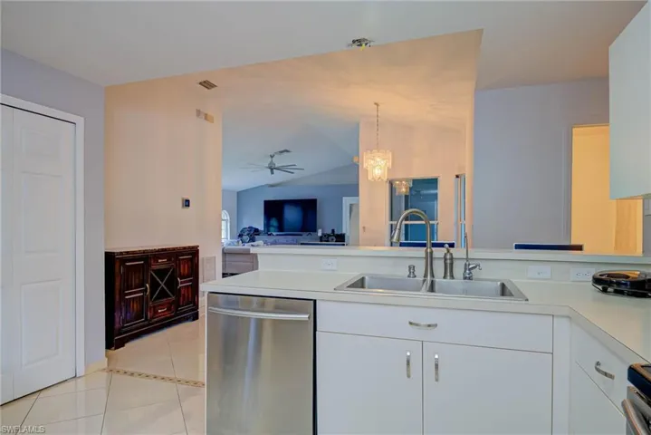 Kitchen featuring light tile patterned floors, stainless steel dishwasher, light countertops, a ceiling fan, and white cabinets