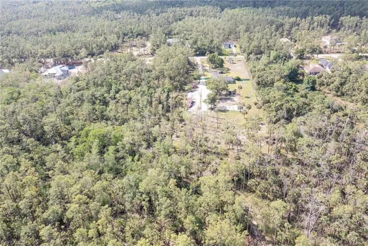 Aerial view of property and surrounding area with a heavily wooded area