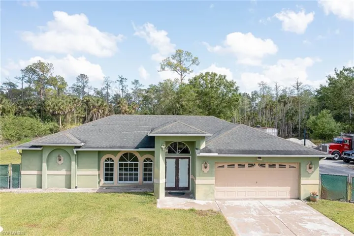 Ranch-style house with stucco siding, a garage, french doors, and concrete driveway