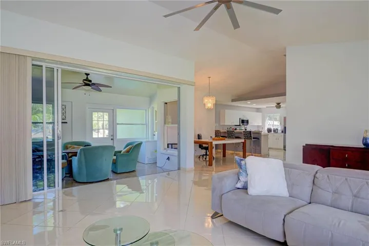 Living room with a ceiling fan, light tile patterned flooring, and lofted ceiling