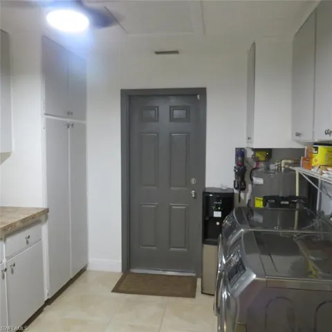 Kitchen with washer and clothes dryer, water heater, and white cabinetry