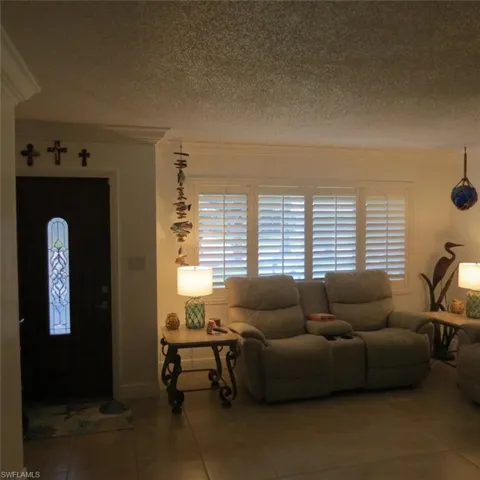 Tiled living room with crown molding and a textured ceiling