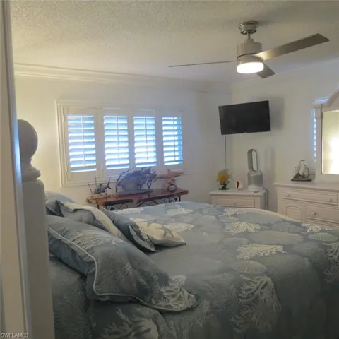 Bedroom with ceiling fan, a textured ceiling, and ornamental molding