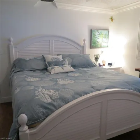 Bedroom featuring crown molding and dark hardwood / wood-style flooring