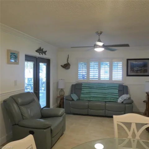 Living room with plenty of natural light, ceiling fan, crown molding, and a textured ceiling
