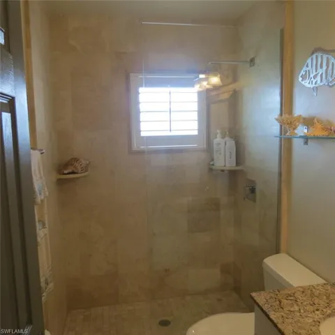 Bathroom featuring a tile shower, vanity, and toilet
