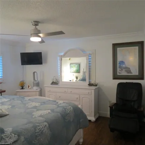 Bedroom with dark hardwood / wood-style floors, crown molding, a textured ceiling, and ceiling fan