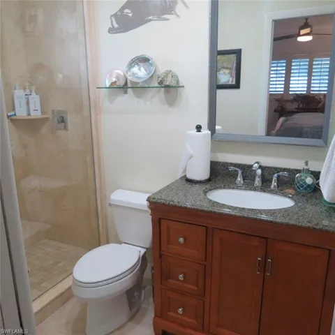 Bathroom with vanity, a shower with shower door, toilet, and tile patterned flooring