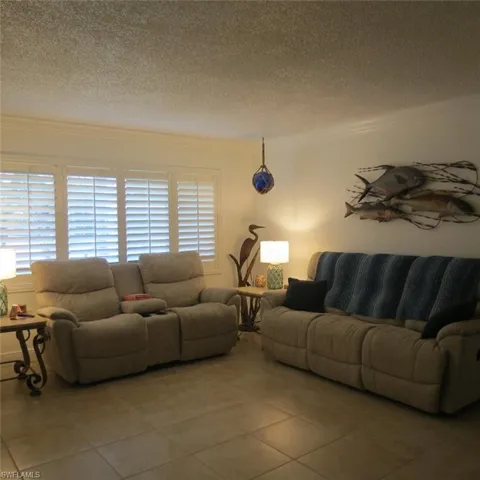 Living room with a textured ceiling, crown molding, and tile patterned flooring