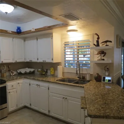 Kitchen featuring white cabinets, stainless steel electric stove, backsplash, and sink