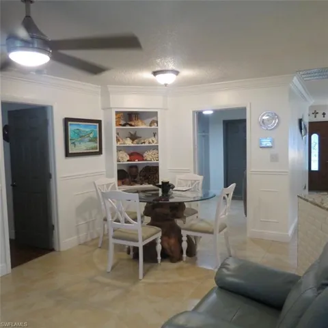 Tiled dining room featuring crown molding, ceiling fan, and a textured ceiling