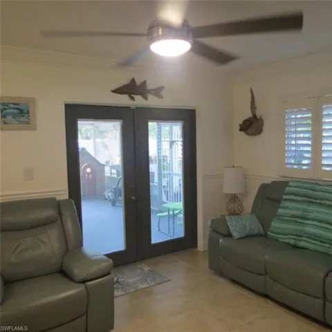 Tiled living room with ornamental molding, ceiling fan, and french doors