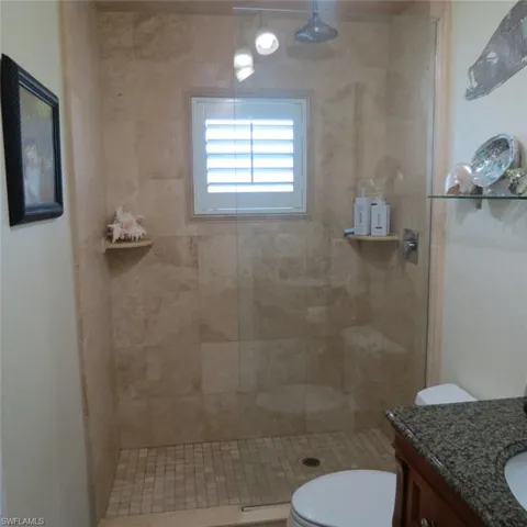 Bathroom featuring a tile shower, vanity, and toilet