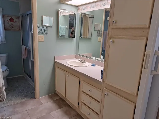Bathroom with walk in shower, tile flooring, toilet, and vanity