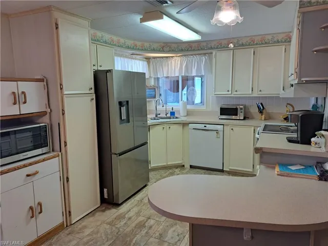 Kitchen with stainless steel appliances, kitchen peninsula, sink, tasteful backsplash, and ceiling fan