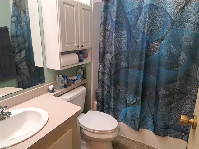 Full bathroom with shower / bathtub combination with curtain, tile flooring, vanity, and toilet