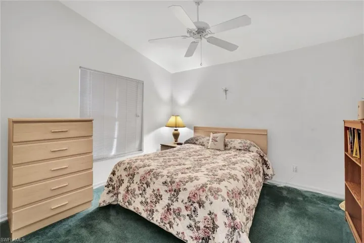 Carpeted bedroom featuring lofted ceiling and ceiling fan
