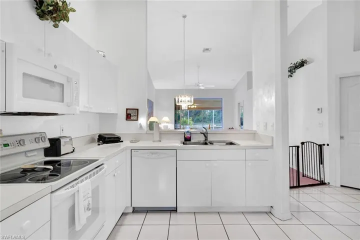 Kitchen featuring white cabinets, high vaulted ceiling, sink, and white appliances