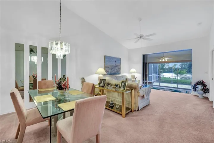 Dining space with light colored carpet, high vaulted ceiling, and ceiling fan with notable chandelier