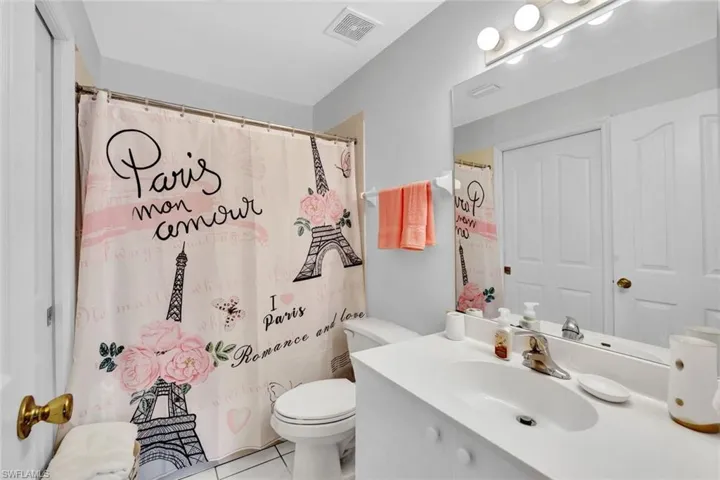 Bathroom featuring vanity, curtained shower, toilet, and tile patterned flooring