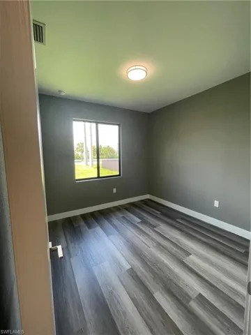 Unfurnished room with baseboards and dark wood-style floors