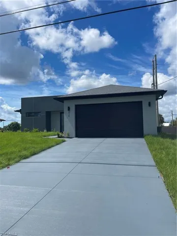 View of front facade featuring stucco siding, a garage, concrete driveway, and a front lawn