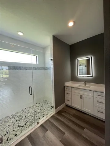 Bathroom featuring vanity, a shower stall, dark wood finished floors, a textured ceiling, and a textured wall