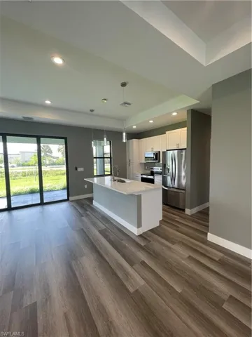 Kitchen with white cabinets, fridge, dark wood-type flooring, stainless steel stove, and a raised ceiling