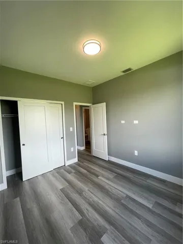 Unfurnished bedroom featuring a closet and dark wood-style floors