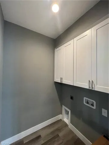 Laundry room featuring hookup for an electric dryer, cabinet space, washer hookup, and dark wood-type flooring