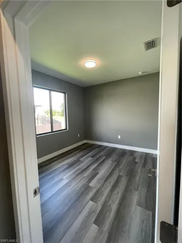 Empty room with dark wood finished floors and baseboards