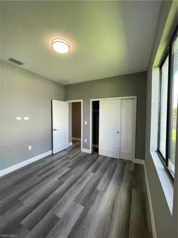 Unfurnished bedroom featuring a closet and dark wood finished floors