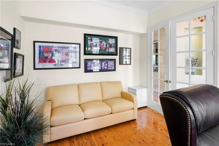Living room with light wood-style floors, ornamental molding, and french doors