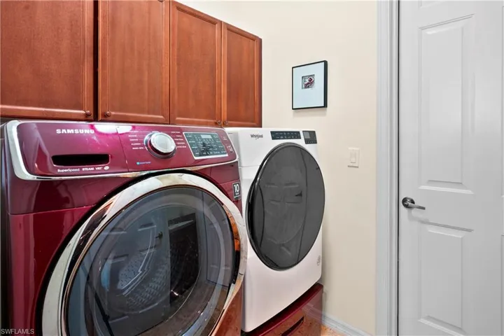 Washroom featuring washing machine and clothes dryer, cabinet space, and baseboards