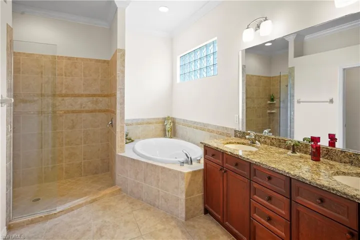 Bathroom featuring tiled shower, a garden tub, double vanity, tile patterned flooring, and crown molding