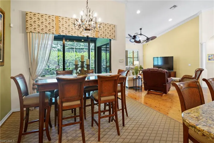 Dining area featuring a chandelier, wood finished floors, ornamental molding, lofted ceiling, and recessed lighting