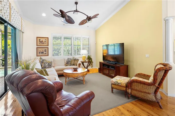 Living room with ceiling fan, crown molding, wood finished floors, ornate columns, and recessed lighting