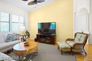 Living room with lofted ceiling, a ceiling fan, and wood finished floors