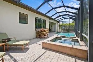 View of pool featuring a patio area, glass enclosure, and a pool with connected hot tub