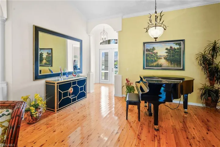Living area with ornate columns, ornamental molding, a chandelier, hardwood / wood-style flooring, and baseboards