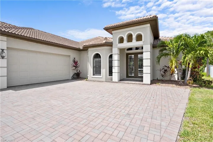 Mediterranean / spanish-style home featuring french doors, a tile roof, a garage, decorative driveway, and stucco siding