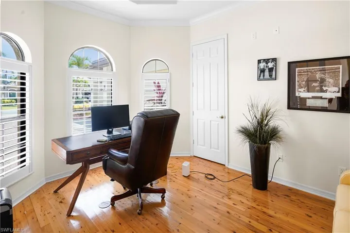 Office space featuring ornamental molding, light wood finished floors, and baseboards