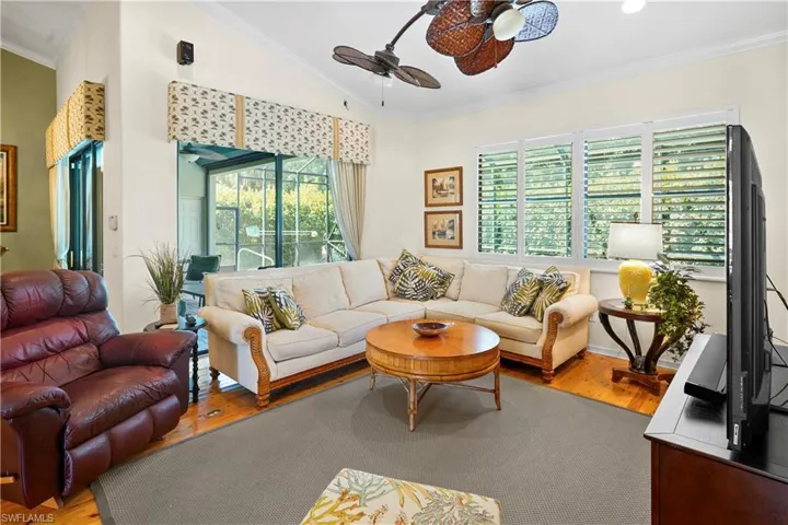 Living room featuring ornamental molding, wood finished floors, a ceiling fan, and lofted ceiling