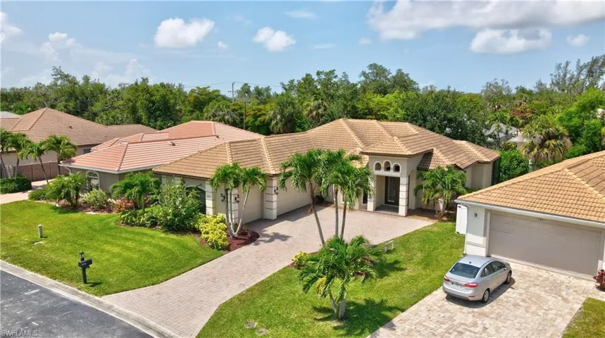Mediterranean / spanish house with decorative driveway, a tiled roof, a front lawn, and an attached garage