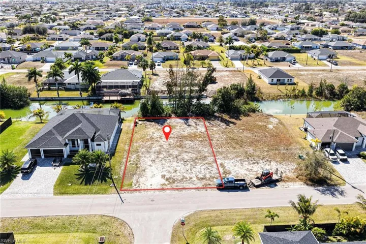 Aerial view of residential area featuring property boundaries highlighted and a large body of water