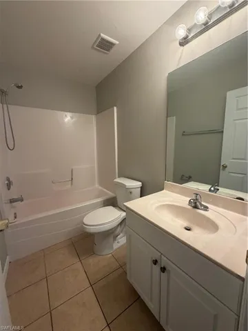 Bathroom with vanity, washtub / shower combination, and light tile patterned floors