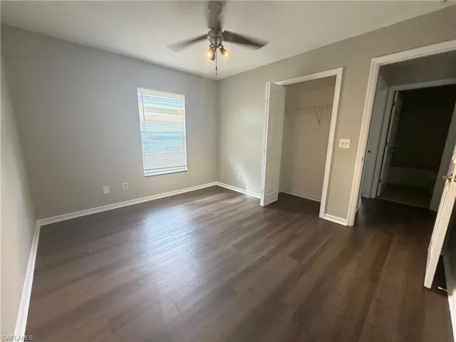 Unfurnished bedroom featuring a closet, dark wood-style flooring, and a ceiling fan